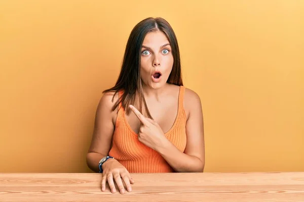 Young Caucasian Woman Wearing Casual Clothes Sitting Table Surprised Pointing — Stock Photo, Image