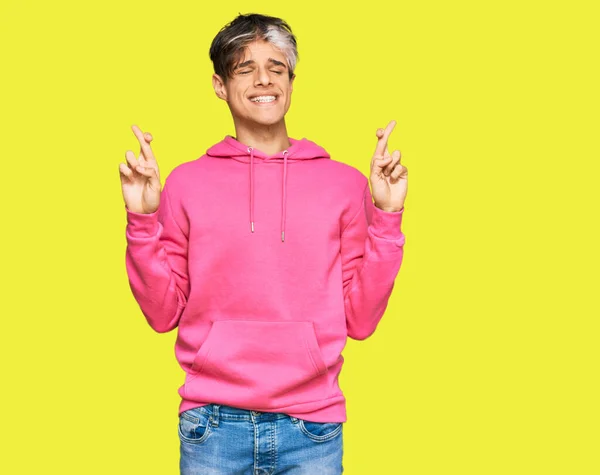 Young Hispanic Man Wearing Casual Pink Sweatshirt Gesturing Finger Crossed — Stock fotografie