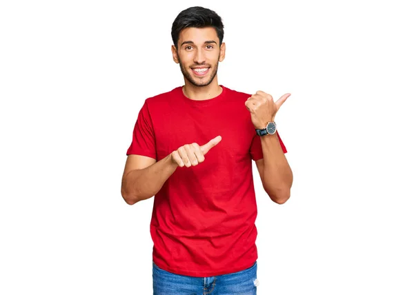 年轻英俊的男子 身穿宽松的红色T恤 手举着大拇指 手背朝后 自信地微笑着 — 图库照片