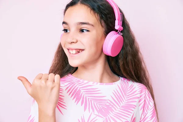 Linda Niña Hispana Escuchando Música Usando Auriculares Apuntando Con Pulgar — Foto de Stock