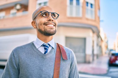 Genç Afrikalı Amerikalı iş adamı gülümseyerek şehirde mutlu bir şekilde yürüyor..