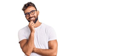 Gündelik giysiler ve gözlük takan genç İspanyol adam kameraya kendinden emin bir şekilde bakıyor kollarını kavuşturup, çenesini kaldırarak gülümsüyor. Olumlu düşünmek. 