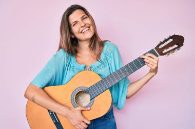 Güzel, beyaz bir kadın klasik gitar çalıyor ve kahkahalarla gülüyor.. 