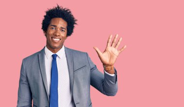 Afro saçlı, iş ceketi giyen yakışıklı Afro-Amerikalı beş numarayı gösterirken kendine güvenen ve mutlu gülümseyen.. 