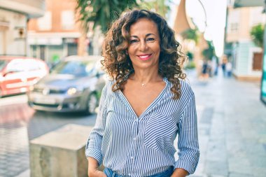 Orta yaşlı İspanyol kadın gülümseyerek şehirde mutlu mesut yürüyor..