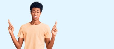 Genç Afro-Amerikalı sıradan kıyafetler giyen, umut ve gözlerin kapalı bir şekilde gülümseyerek el işareti yapan genç bir adam. Şans ve batıl inançlar. 