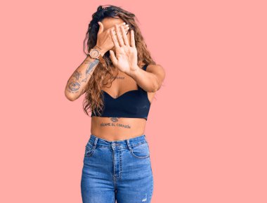 Gündelik kıyafetler giyen, gözlük takan, gözlerini elleriyle kapatan, üzgün ve korku ifadeli İspanyol genç bir kadın. utangaç ve olumsuz kavram. 