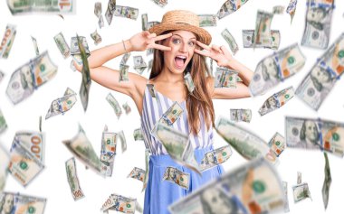 Genç, sarışın, yaz şapkası takan, barış sembolü yapan, yüzünde parmakları olan, gülümseyen, zaferi gösteren güzel bir kadın.