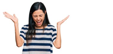 Başarılı olmak için çılgınca ve çılgınca kutlamalar yapan gündelik kıyafetler giyen güzel genç bir kadın. Kollarını kaldırmış, gözlerini kapatmış heyecanlı çığlıklar atıyordu. Kazanan konsept 