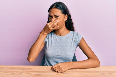 Genç Afro-Amerikan kızı, gündelik kıyafetlerini giymiş masaya oturmuş pis ve iğrenç bir koku alıyor. Dayanılmaz bir koku. Parmaklarını burnuna dayamış nefesini tutuyor. Kötü kokuyor. 