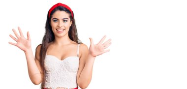 Zarif görünümlü esmer kız on numarayı gösterip işaret ederken kendinden emin ve mutlu gülümsüyor.. 