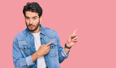 Gündelik kıyafetler giyen genç İspanyol bir adam iki eliyle endişeli ve endişeli bir ifadeye işaret ediyor. 