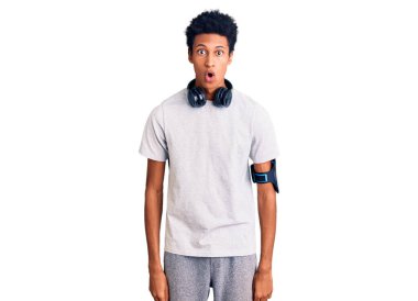 Genç Afro-Amerikan adam spor kıyafetleri giyiyor ve kulaklık kullanıyor. Korkmuş ve ağzı açık bir şekilde şaşırmış, inançsız bir yüz. 