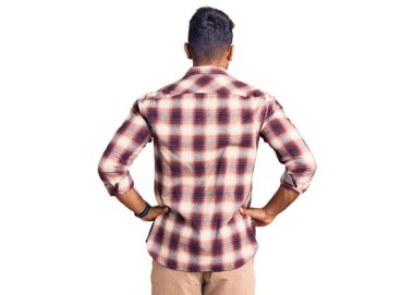 Gündelik kıyafetler ve gözlük takan genç İspanyol adam kolları vücudunda geriye doğru bakıyor. 