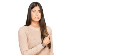 Kışlık süveter giyen genç esmer kadın endişeli ve gergin bir şekilde işaret ediyor. 