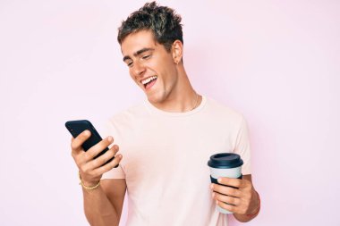 Akıllı telefon kullanan yakışıklı bir adam kahveyi alıp götürür kahkahalarla güler ve kahkahalarla güler.. 
