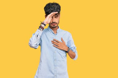 Günlük kıyafetler giyen genç İspanyol adam hastalık, ateş, grip ve virüs için alnına dokunuyor. 