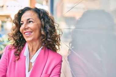 Orta yaşlı İspanyol iş kadını şehirde mutlu bir şekilde ayakta duruyor..