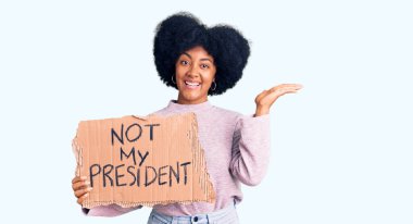 Genç Afro-Amerikan kızı, başkanım protesto pankartı tutmuyor zaferi mutlu bir gülümsemeyle kutluyor ve kazanan ifade ellerini kaldırıyor. 