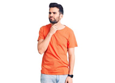 Sakallı, sıradan tişörtlü, boynu ağrıyan, boğazı ağrıyan, grip, mantar ve enfeksiyon kapmış genç yakışıklı bir adam. 