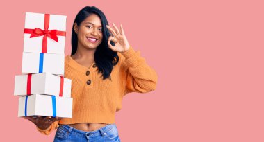 Uzun saçlı İspanyol kadın hediyeler tutuyor. Parmaklarıyla imza atıyor. Gülümsüyor. 