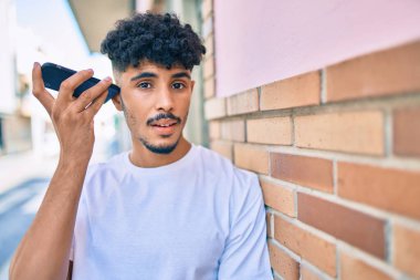 Genç Arap adam şehirdeki akıllı telefonu kullanarak sesli mesaj dinliyor.