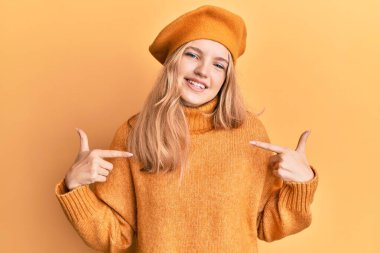 Fransız elbisesi giymiş güzel beyaz bir kız. Bere takmış, kendine güvenen, gülümseyen, kendini gururlu ve mutlu bir şekilde gösteren bir kız.. 