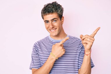 Gündelik kıyafetler giyen, gülümseyen ve kameraya bakan genç, yakışıklı bir adam.. 