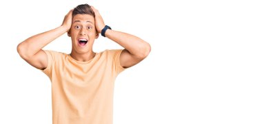 Genç, yakışıklı, sıradan kıyafetler giyen çılgın ve elleri başında korkmuş, korkmuş ve ağzı açık şoktan şaşırmış bir adam. 