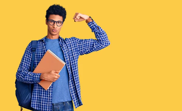 若いアフリカ系アメリカ人男性学生リュックを保持本強い人を示す腕の筋肉 自信と力の誇り — ストック写真