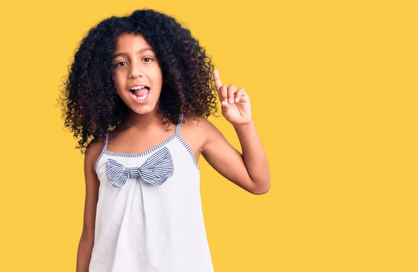 カジュアルな服を着て巻き毛を持つアフリカ系アメリカ人の子供は 成功したアイデアで指を指す 興奮して幸せよ 第1位 — ストック写真