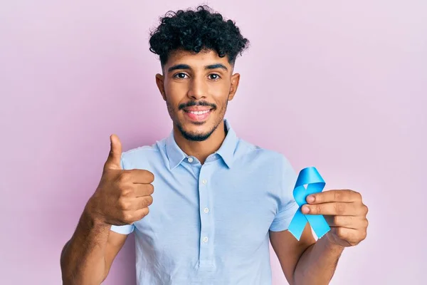 Mladý Arabský Pohledný Muž Drží Modrou Stuhu Usmívá Šťastný Pozitivní — Stock fotografie