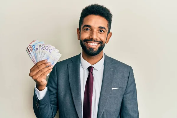 Przystojny Młody Latynoski Biznesmen Trzymający Szwedzkie Banknoty Korony Wyglądający Pozytywnie — Zdjęcie stockowe