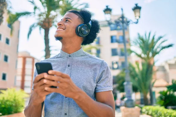 アフリカ系アメリカ人の若者が市内のスマートフォンやヘッドフォンを使って笑顔で — ストック写真