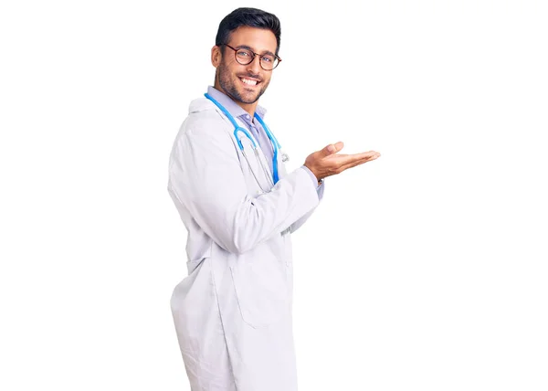 Joven Hombre Hispano Vistiendo Uniforme Médico Estetoscopio Señalando Lado Con —  Fotos de Stock