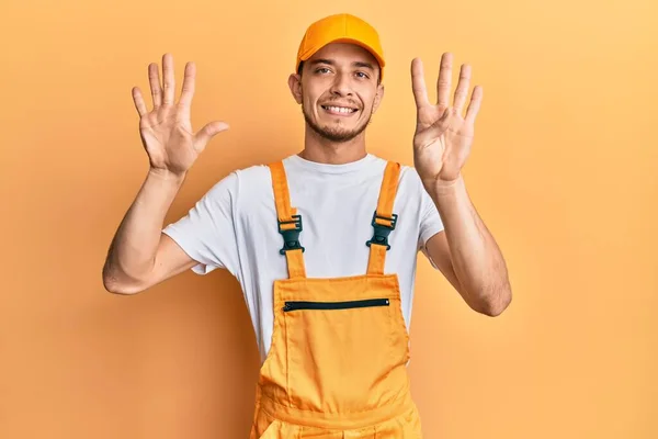 Mladý Hispánec Kutilské Uniformě Ukazující Ukazováčkem Stranu Reklamou Vážnou Klidnou — Stock fotografie