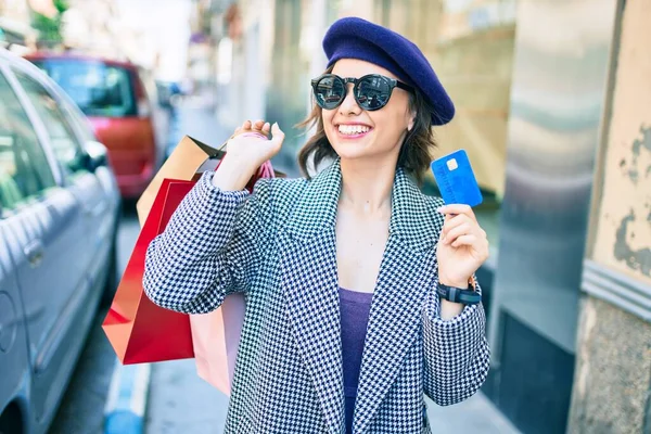 年轻美丽的姑娘笑着 她喜欢法国式的手拿着购物袋和信用卡在城市的街道上 — 图库照片