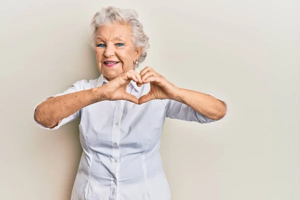 高个子灰发女人穿着休闲装 带着爱的笑容用手做心形符号 浪漫的概念 — 图库照片
