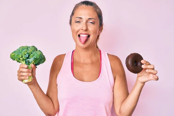 Hispanische Frau Mittleren Alters Hält Brokkoli Und Schokokrapfen Der Hand — Stockfoto