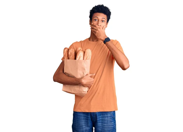 Молодой Африканский Американец Держит Бумажный Пакет Хлебом Шоке Прикрывая Рот — стоковое фото