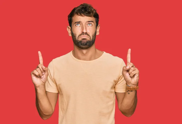 Jovem Bonito Com Barba Vestindo Camiseta Casual Apontando Para Cima — Fotografia de Stock