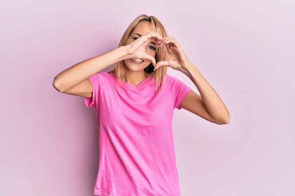 Mulher Loira Bonita Vestindo Camiseta Rosa Casual Fazendo Forma Coração — Fotografia de Stock