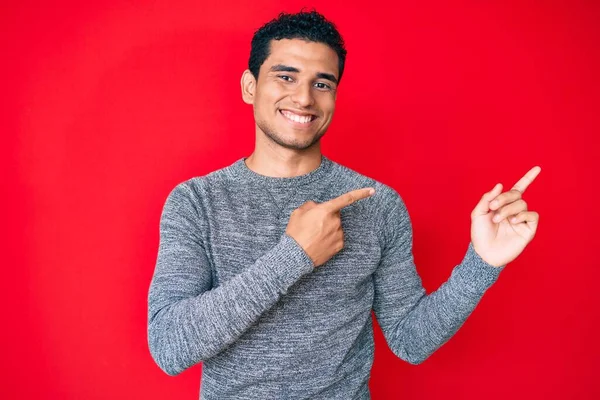 Pemuda Tampan Hispanik Atas Latar Belakang Merah Tersenyum Dan Melihat — Stok Foto