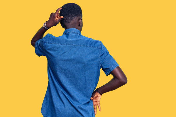 Young african american man wearing casual clothes backwards thinking about doubt with hand on head