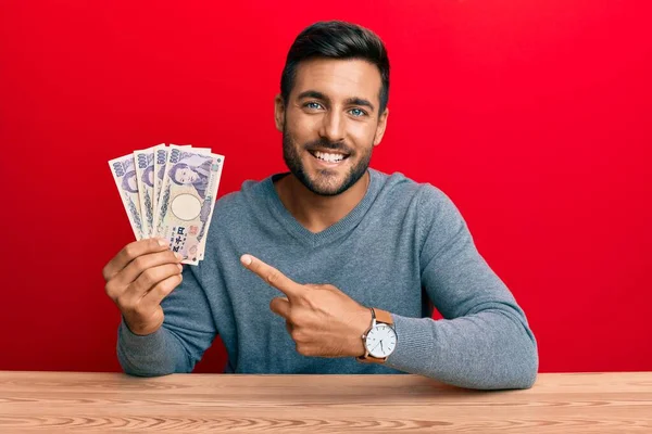 手と指で笑顔で日本円の紙幣を持っているハンサムなヒスパニック系の男 — ストック写真