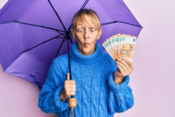 中世ブロンド女性保持傘と50ユーロ紙幣作り魚顔とともに口と角質目 クレイジーとコミカルな — ストック写真