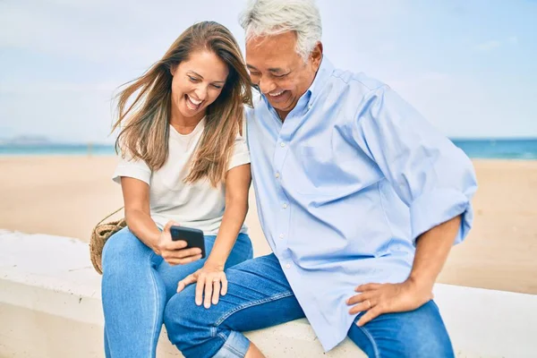 Medelålders Latinamerikanska Par Använder Smartphone Sitter Bänken Stranden — Stockfoto