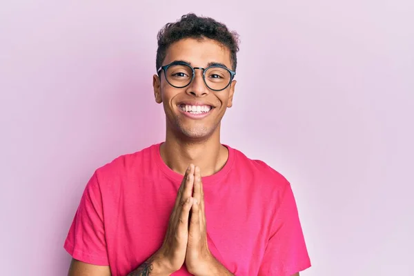 Fiatal Jóképű Afro Amerikai Férfi Szemüveget Visel Rózsaszín Háttér Imádkoznak — Stock Fotó