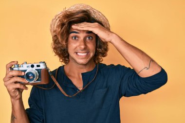 Şapka takan İspanyol genç adam, elinde eski model kamerayla gergin ve hayal kırıklığına uğramış, şaşırmış ve kızgın bir yüzle. 