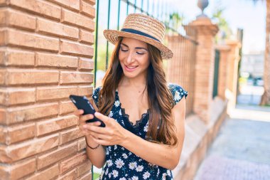 Genç İspanyol kadın şehir caddesinde akıllı telefon kullanıyor..